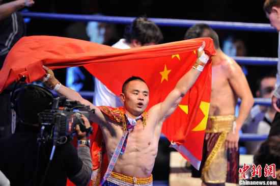 资料图:WBC迷你轻量级世界拳王金腰带争霸赛在昆明举行,矿工出身的云南籍职业拳手熊朝忠击败墨西哥拳王哈维尔·马丁内斯,成为中国首位世界拳王。图为比赛结束后熊朝忠身披国旗。中新社发 刘冉阳 摄 挑战日本拳坛大魔王遭KO 可乌兰说他还敢再来一
