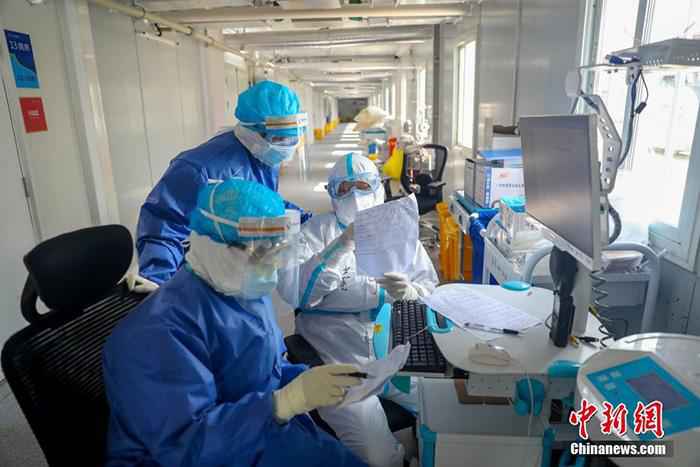 火神山医院感染二科一病区主任董宇超(白衣者)与同事一起查对患者信息。中新社记者 张畅 摄 探访火神山医院:看到解放军就觉得安心
