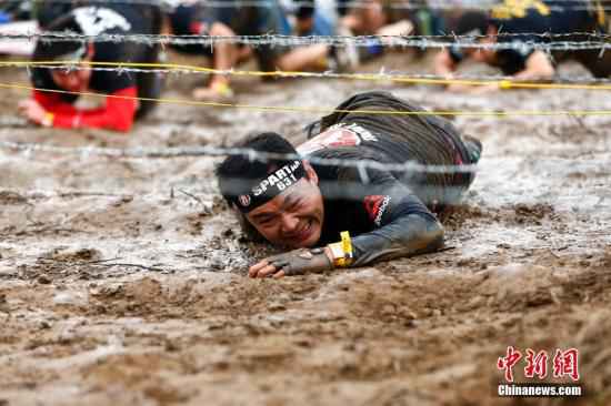 资料图:斯巴达勇士赛(Spartan Race)北京站开赛,本站全程6公里,设有俄尔普斯之禁、胜利之矛、人猿泰山、海格力斯之臂等21个障碍供勇士挑战,吸引了3000名中外长跑、障碍跑及健身爱好者参与其中,中国短跑名将张培萌及前体操世界冠军陈一冰一同参加挑战。 中新社记者 富田 摄 爬泥地、跨明火、越障碍……中国人也能当斯巴